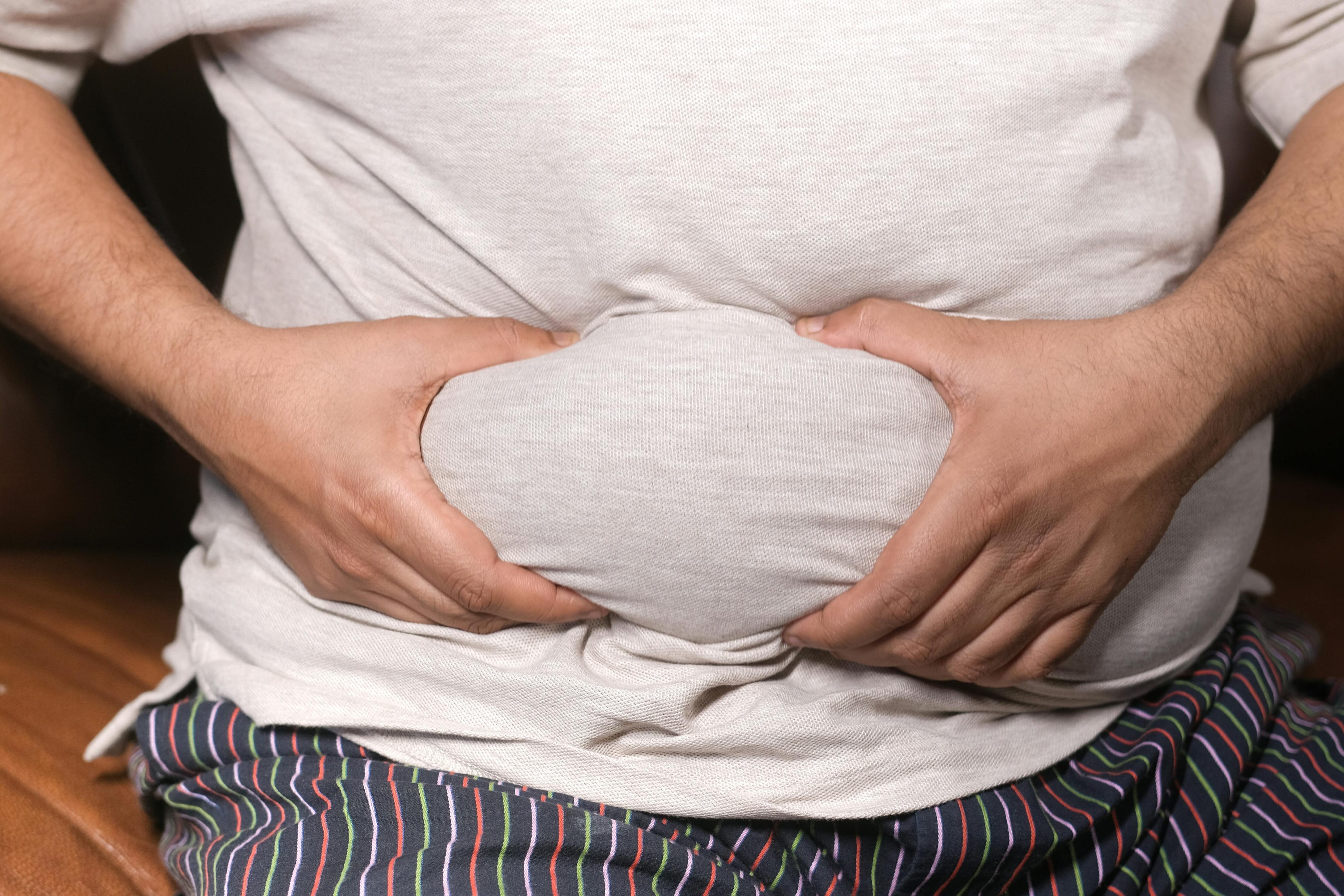 Man looking at his body in the mirror after weight loss, noticing saggy skin and body changes
