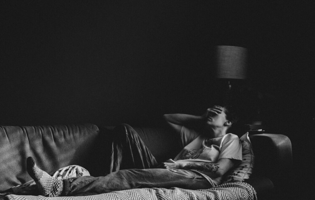 person lying tired on couch showing low energy from long term lack of exercise