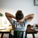 person sitting hunched over desk looking stiff and uncomfortable