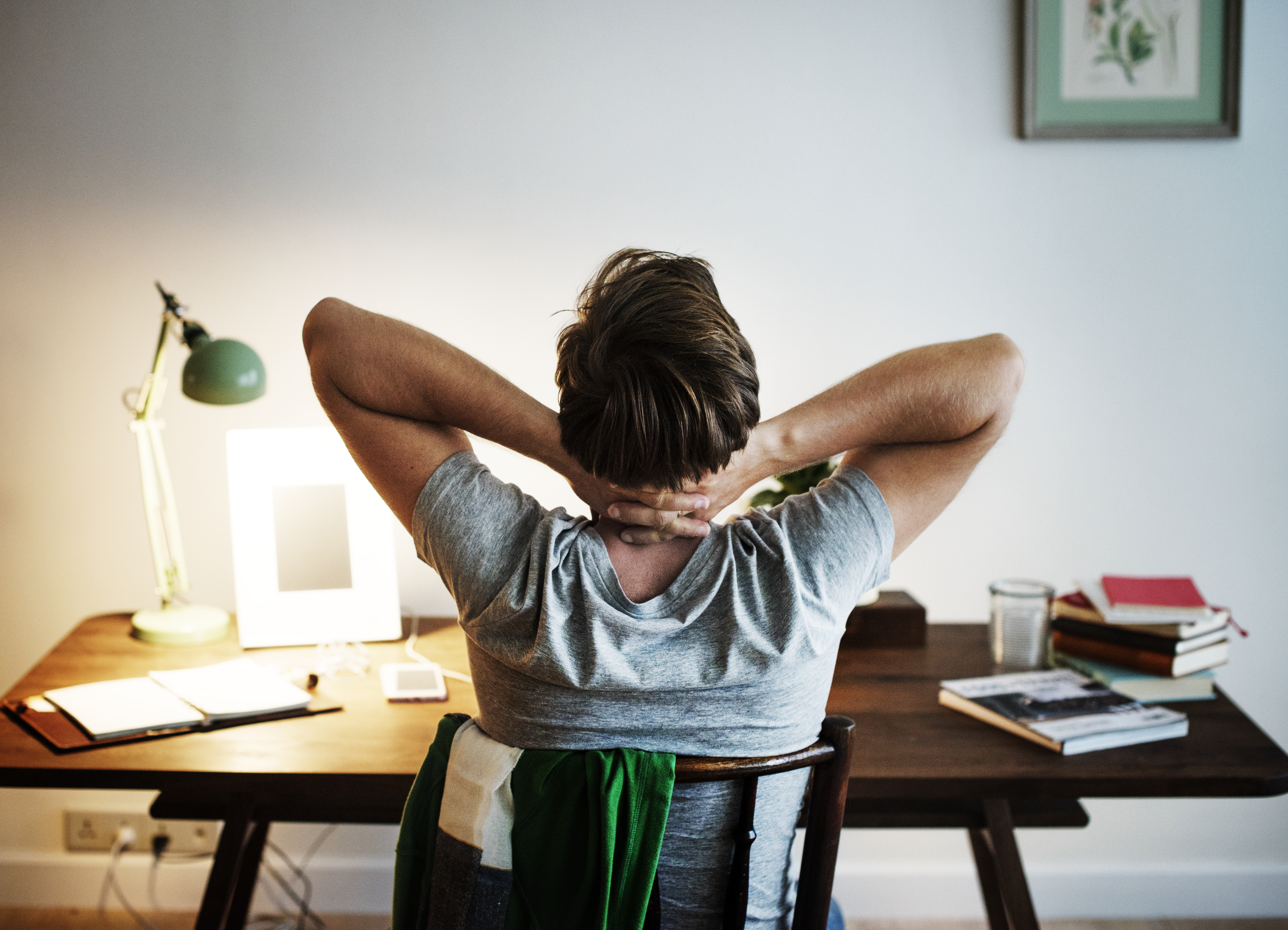 person sitting hunched over desk looking stiff and uncomfortable