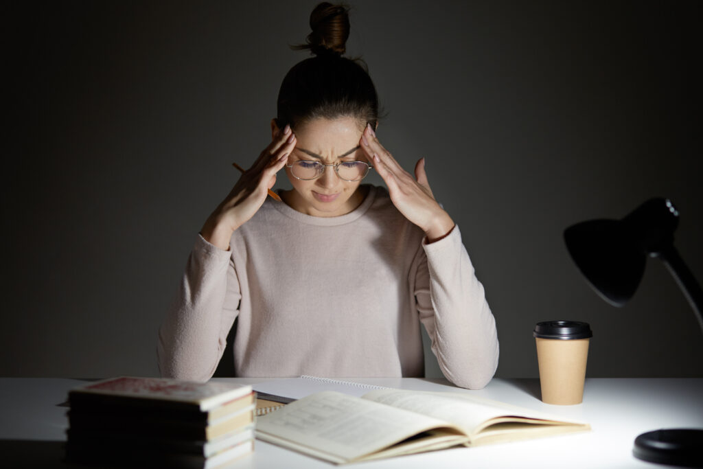 person staring at laptop screen unfocused looking mentally drained
