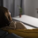 person sitting on couch feeling tired with cold hands and low energy signs