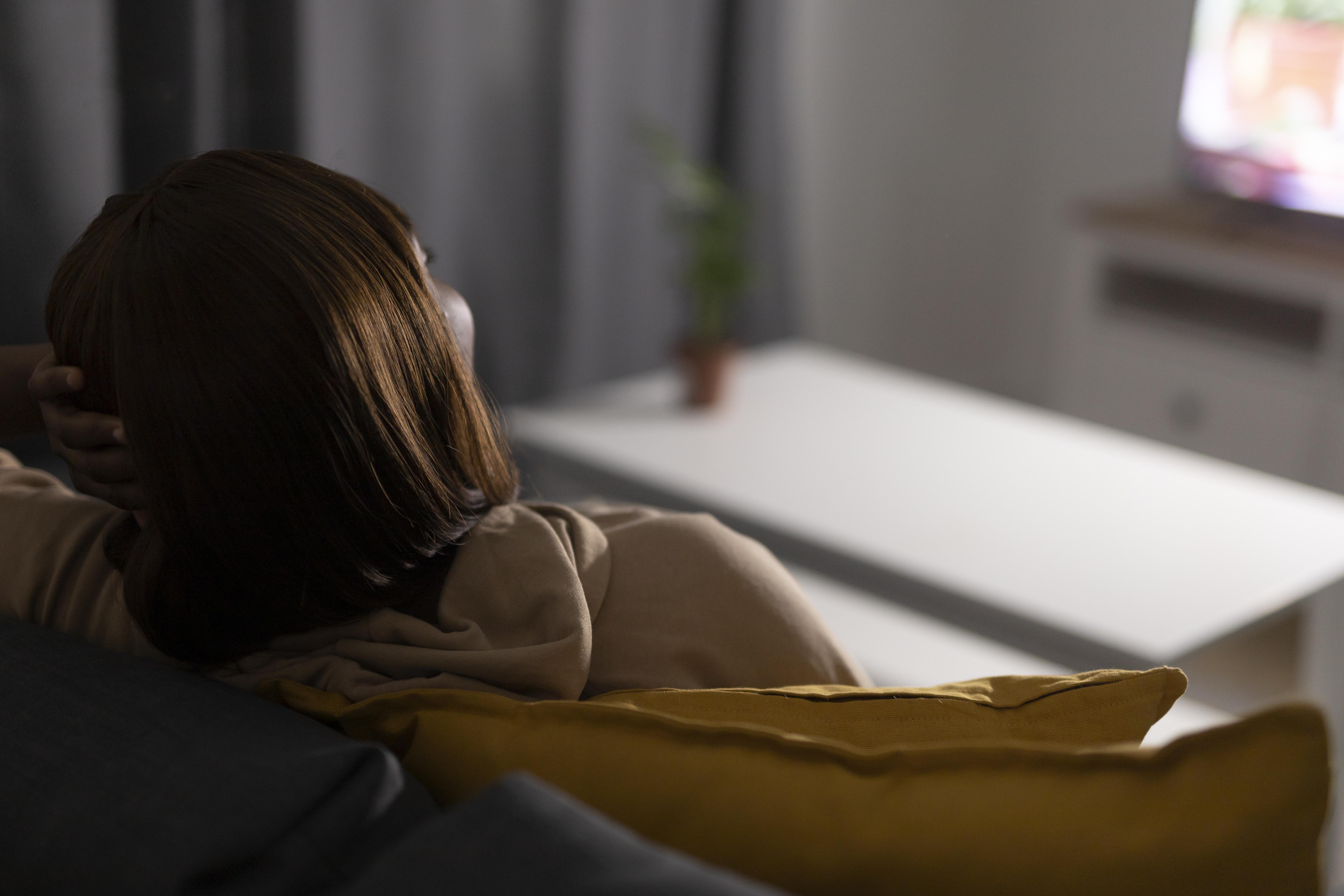 person sitting on couch feeling tired with cold hands and low energy signs