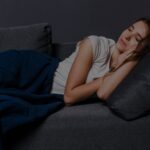 person lying in bed awake at night staring at the ceiling in a dark room