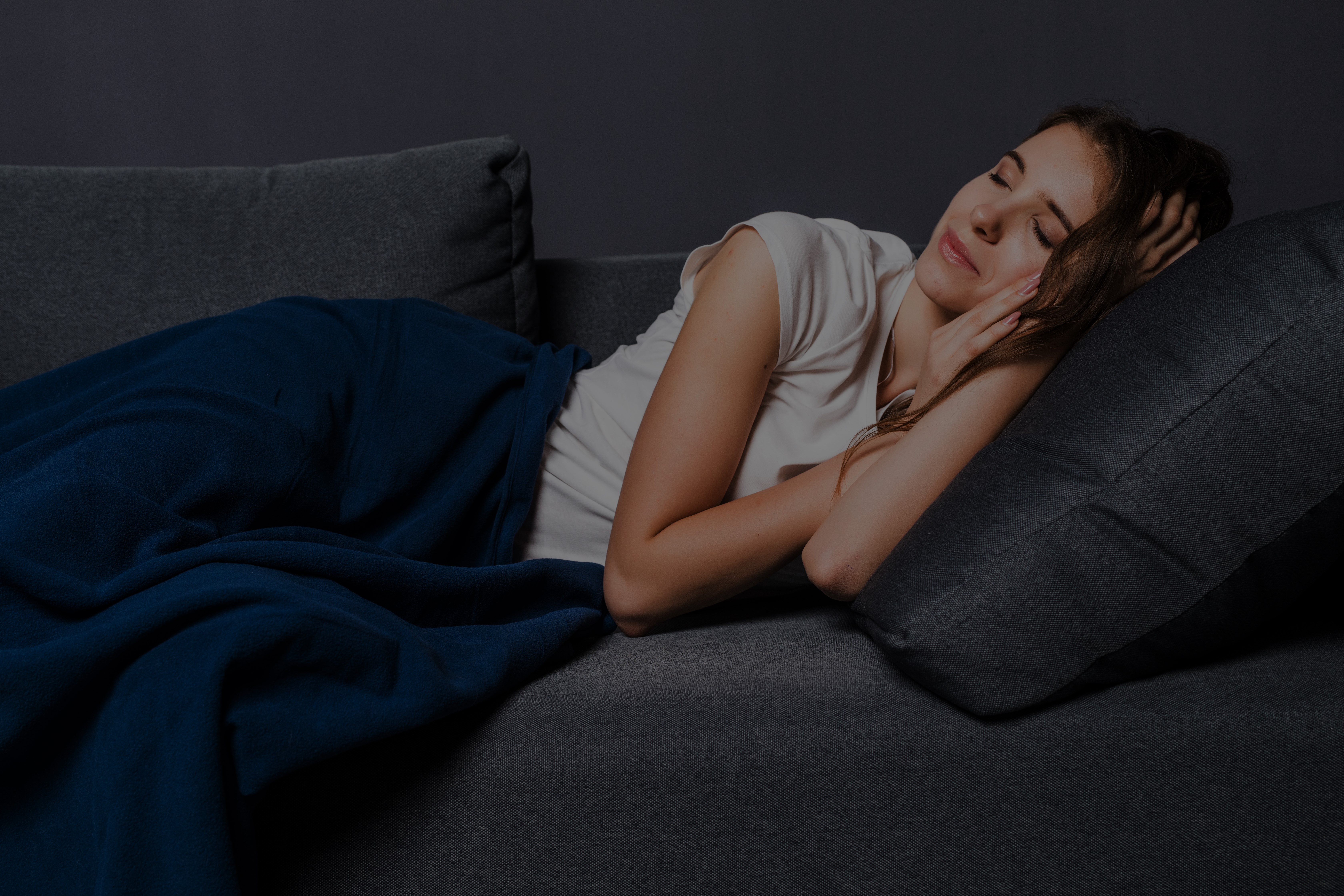 person lying in bed awake at night staring at the ceiling in a dark room