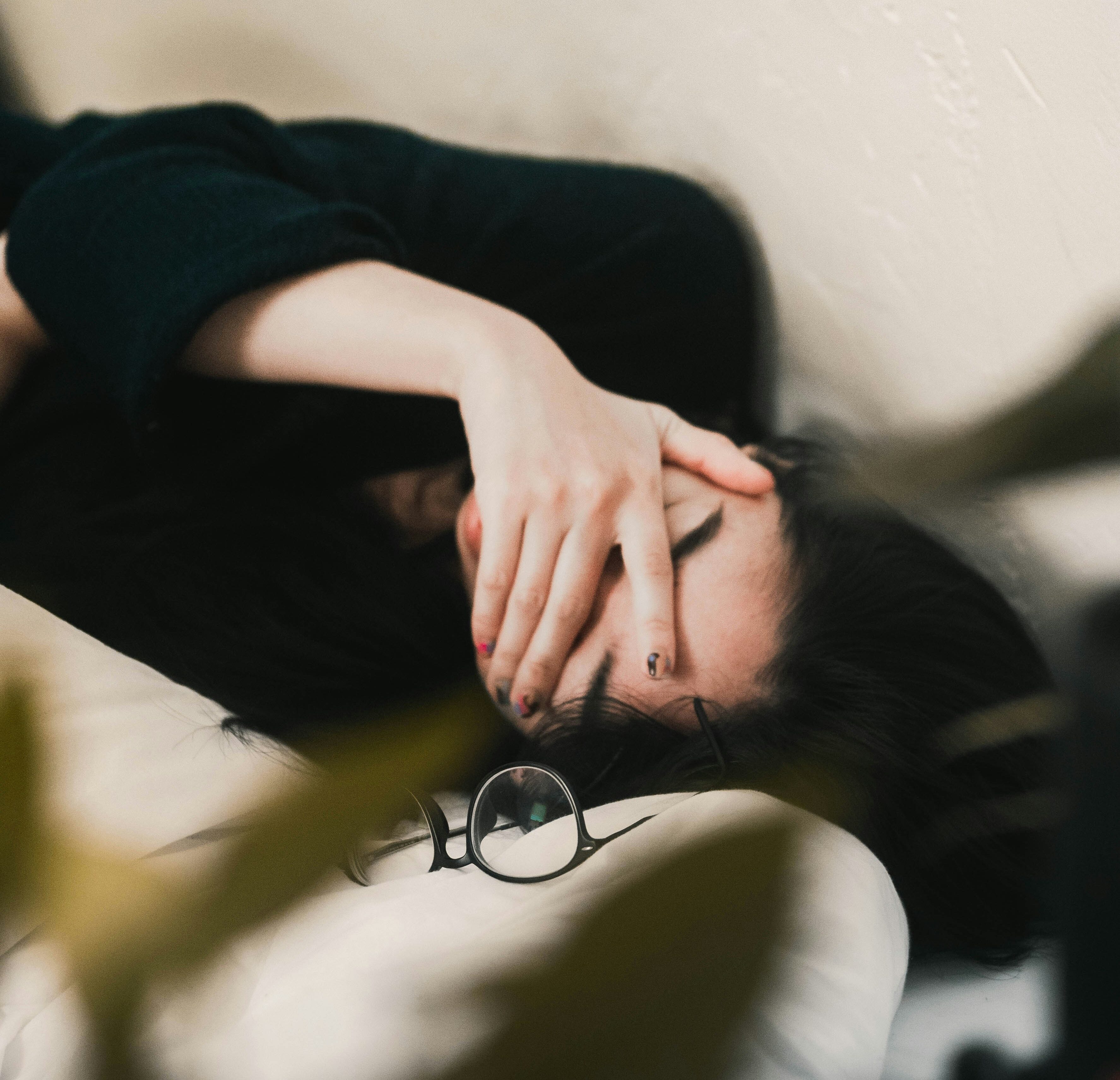 person laying down on the bed hand on eyes